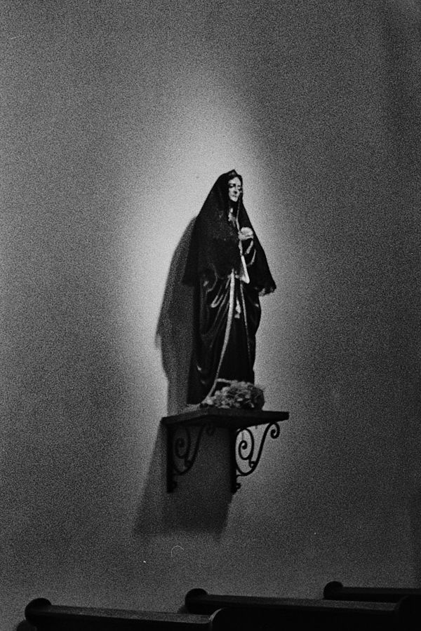 Figura de la Virgen en un nicho iluminado sobre un muro blanco