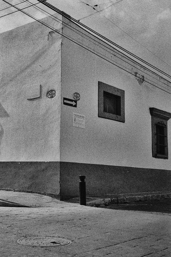 Esquina de una casa colonial con ventanas enmarcadas y cables de luz